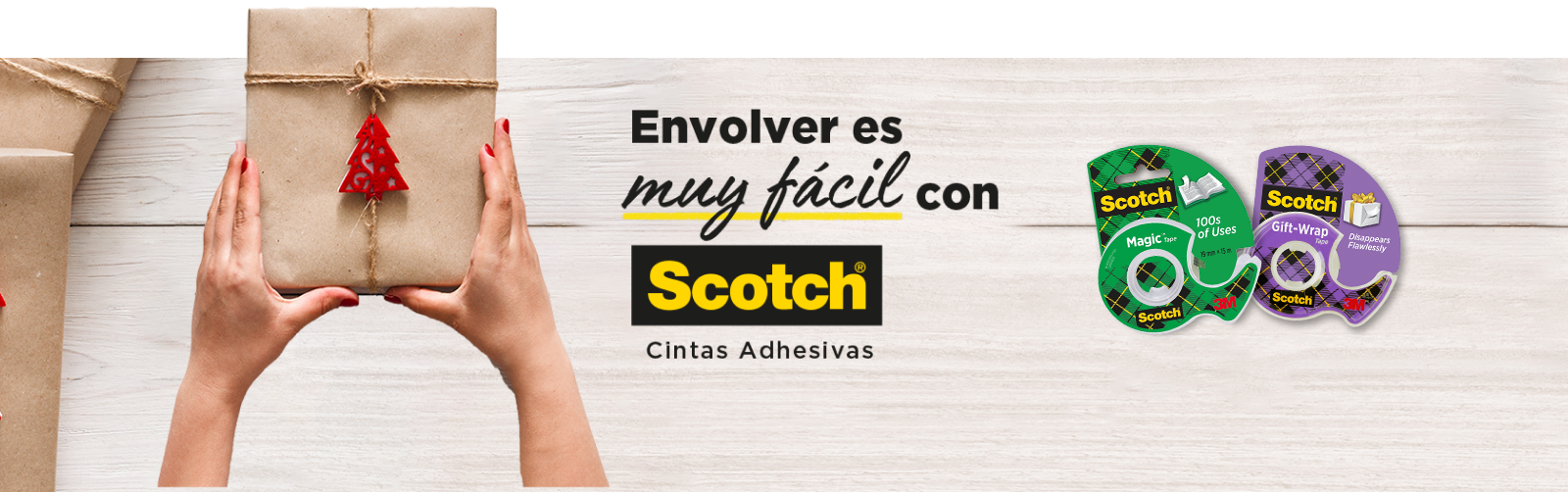 Manos de mujer sosteniendo regalo sobre una mesa que tiene Cinta Mágica™ Scotch® y Cinta de Regalo Scotch®.